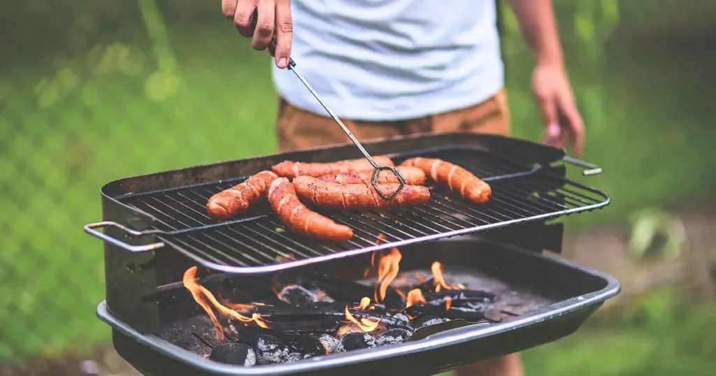 A man cooking breakfast on a Blackstone griddle outdoors, flipping pancakes and frying bacon on its expansive, evenly heated surface.