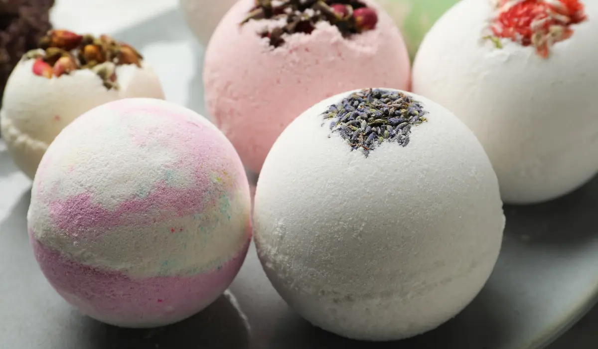 A close-up image of homemade Elderberry Bombs, small round gummy-like supplements made with white and pink elderberry extract, displayed on a light wooden surface.