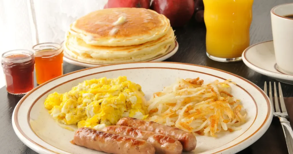 hearty breakfast plate featuring deer sausage links, scrambled eggs, and toasted whole grain bread, served on a rustic wooden table