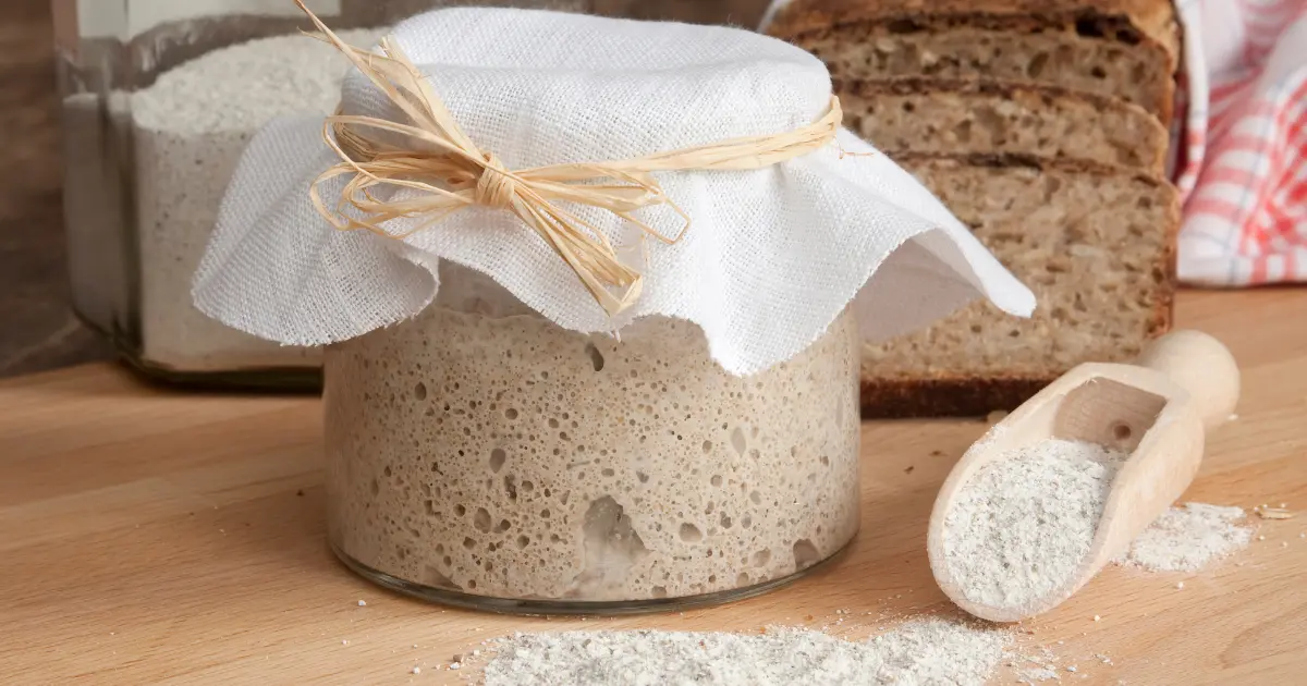 Sliced sourdough bread on a wooden board, highlighting its airy texture and golden crus