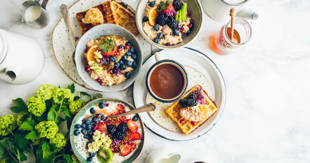 A colorful array of PCOS-friendly breakfast dishes including a bowl of oatmeal topped with berries, a plate of spinach omelette, and a glass of green smoothie.