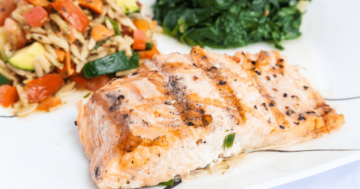 Grilled salmon fillet served on a bed of sautéed spinach and mixed vegetables, highlighting a healthy and colorful meal option