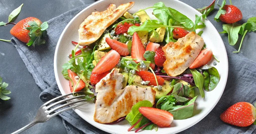 An image of a fresh chicken salad, featuring crisp lettuce, sliced cucumbers, ripe strawberries, and grilled chicken breast pieces. Perfect choice for Lunch Without Gluten?