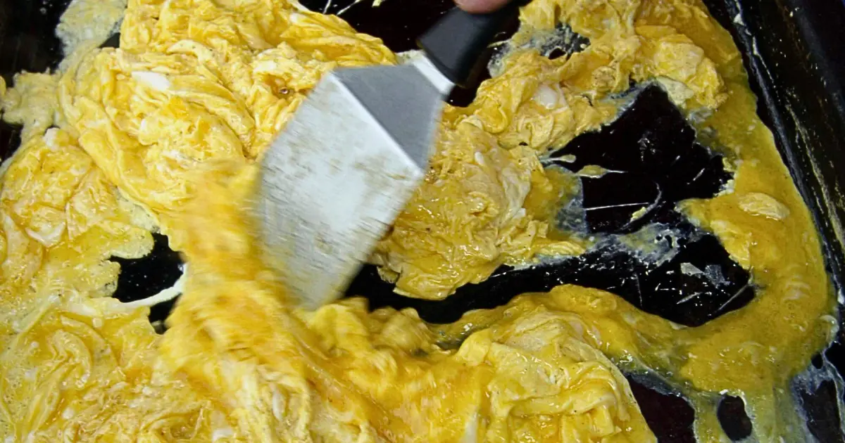 Eggs sticking to the surface of a Blackstone griddle, showing patches of cooked egg whites adhered to the dark, seasoned metal.