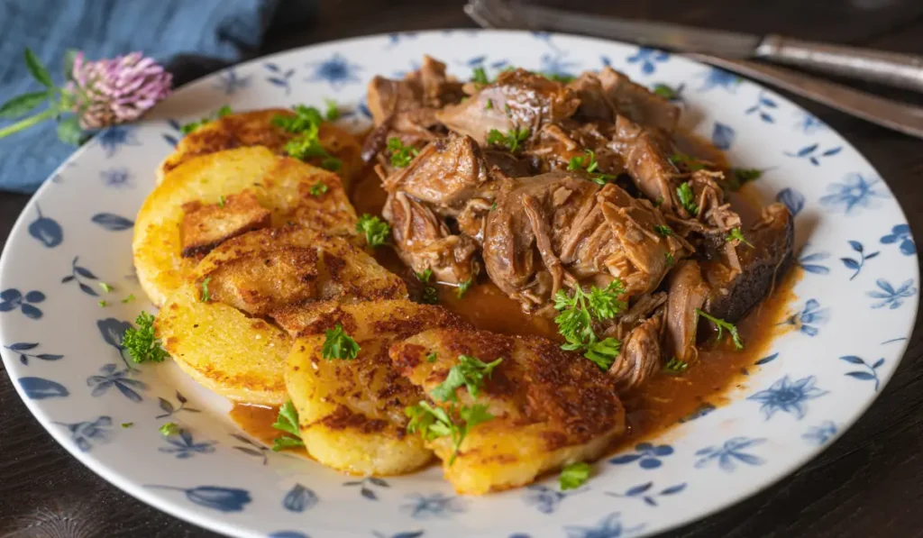 A plate of leftover pot beef roast served with golden potato slices.